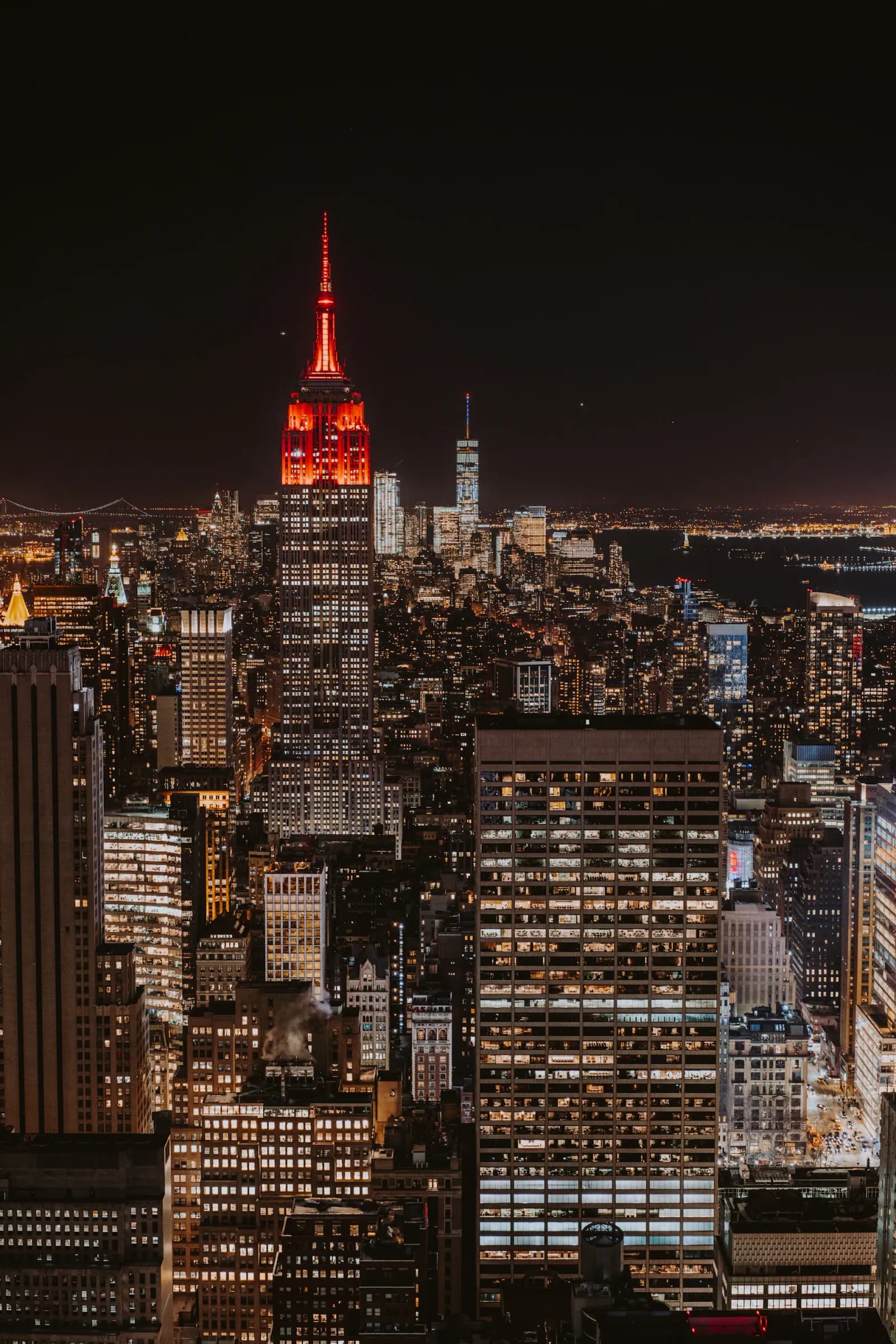 Manhattan la nuit, avec l'Empire State Building illuminé en rouge